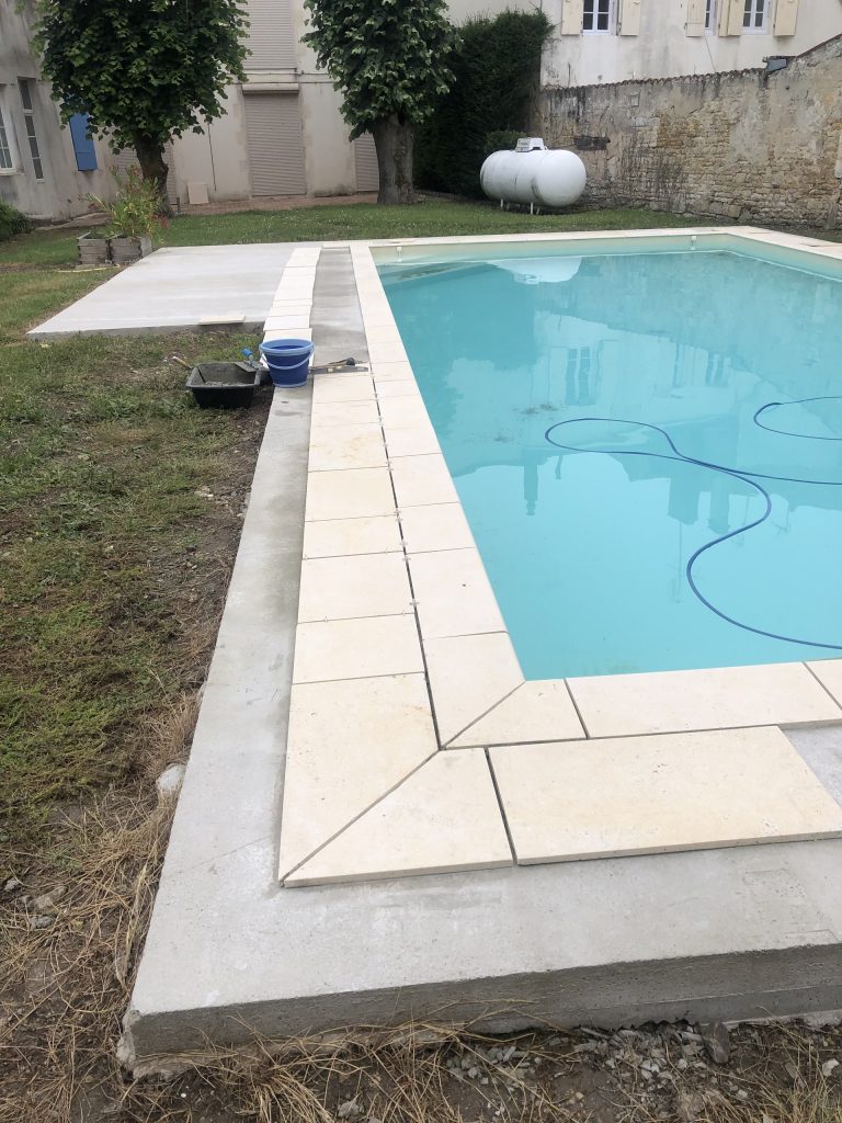 Pose des margelles et dallage en pierre autour d'une piscine à MARANS