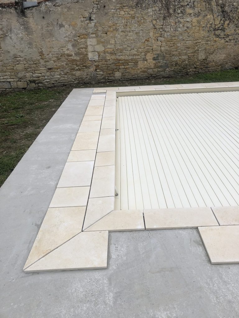 Pose des margelles et dallage en pierre autour d'une piscine à MARANS