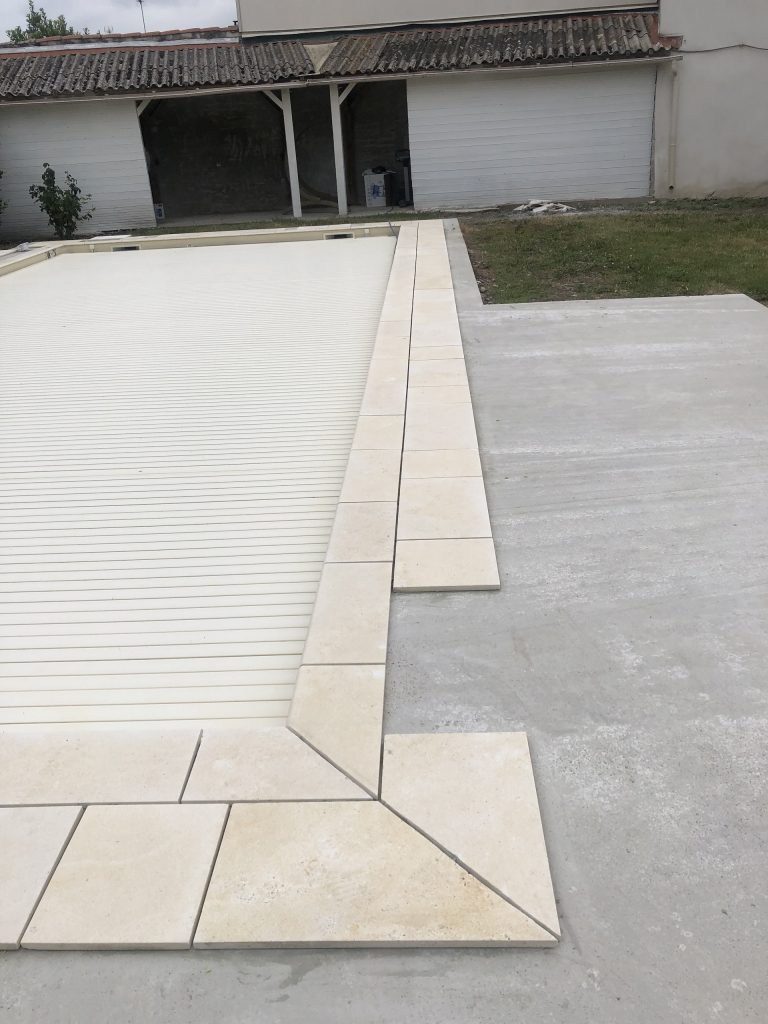 Pose des margelles et dallage en pierre autour d'une piscine à MARANS