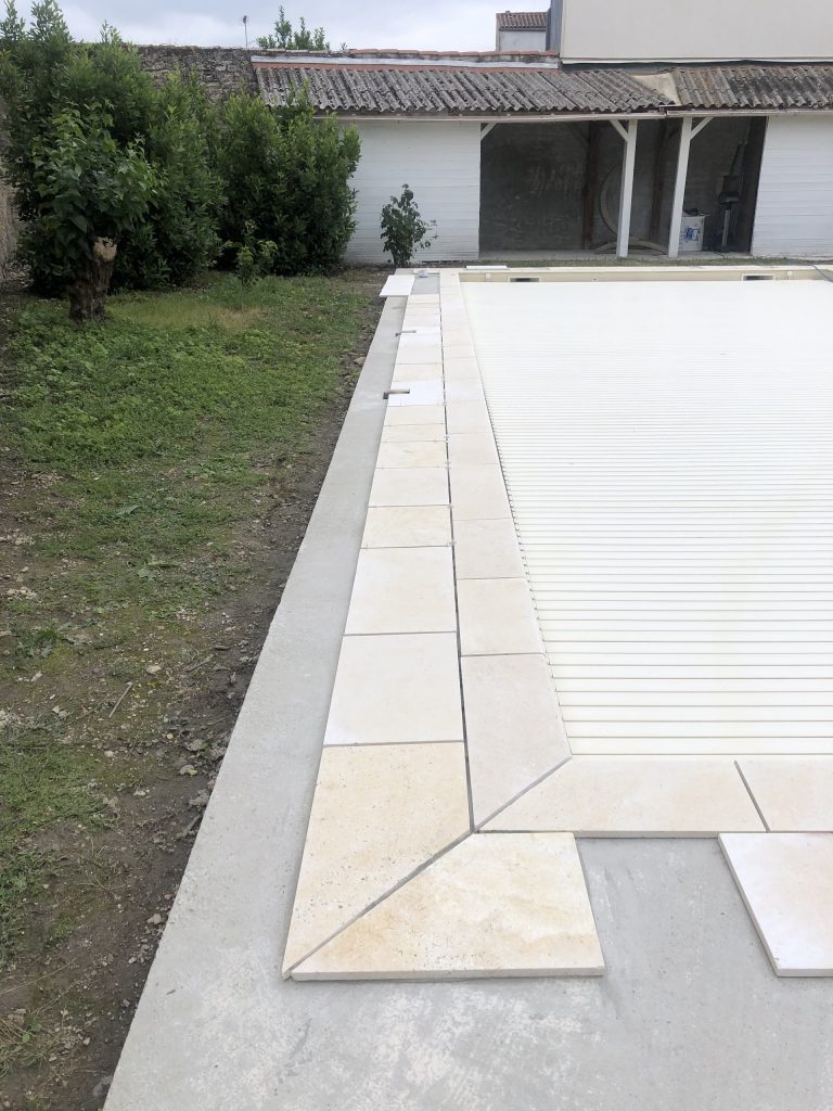 Pose des margelles et dallage en pierre autour d'une piscine à MARANS