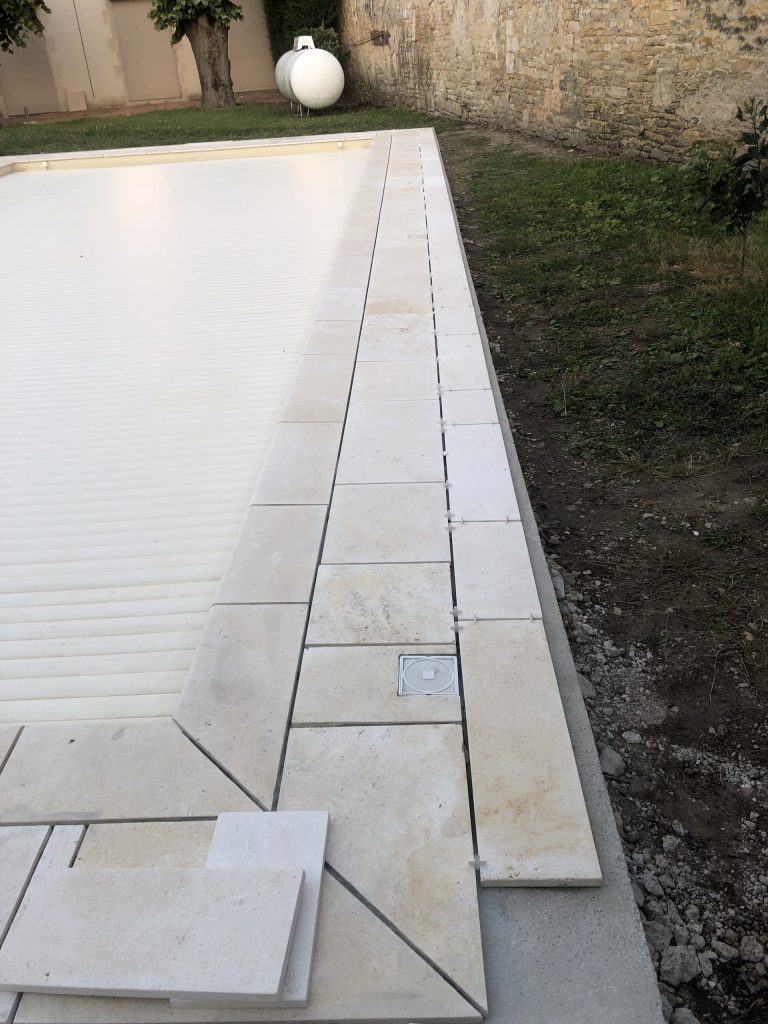 Pose des margelles et dallage en pierre autour d'une piscine à MARANS