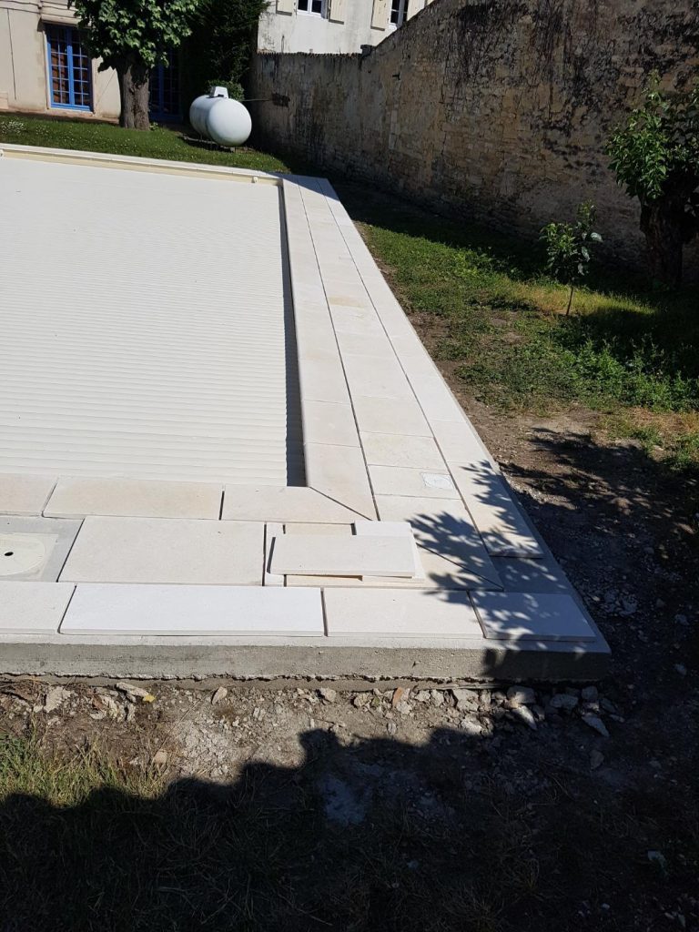 Pose des margelles et dallage en pierre autour d'une piscine à MARANS