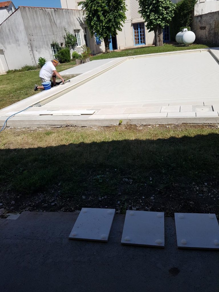 Pose des margelles et dallage en pierre autour d'une piscine à MARANS