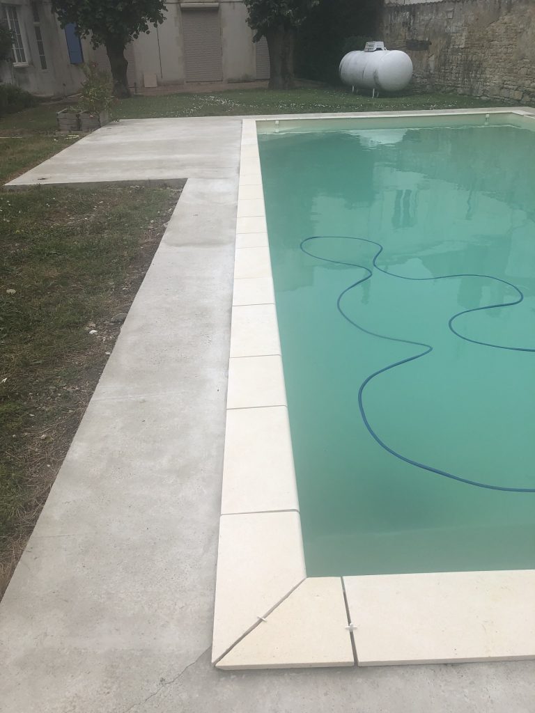 Pose des margelles et dallage en pierre autour d'une piscine à MARANS