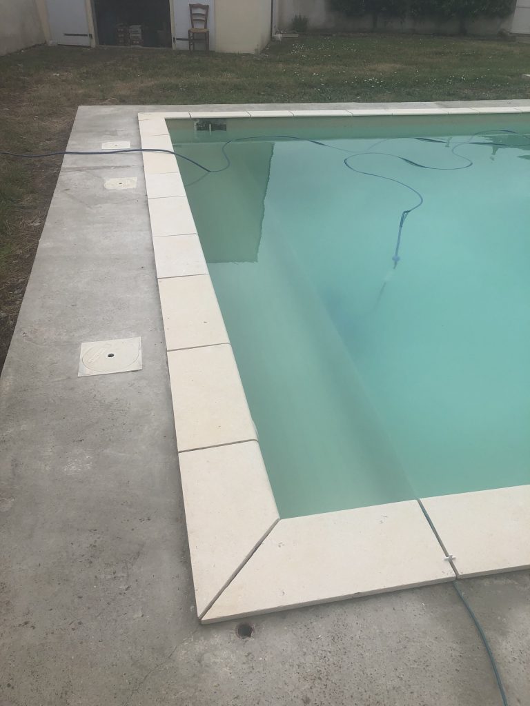 Pose des margelles et dallage en pierre autour d'une piscine à MARANS
