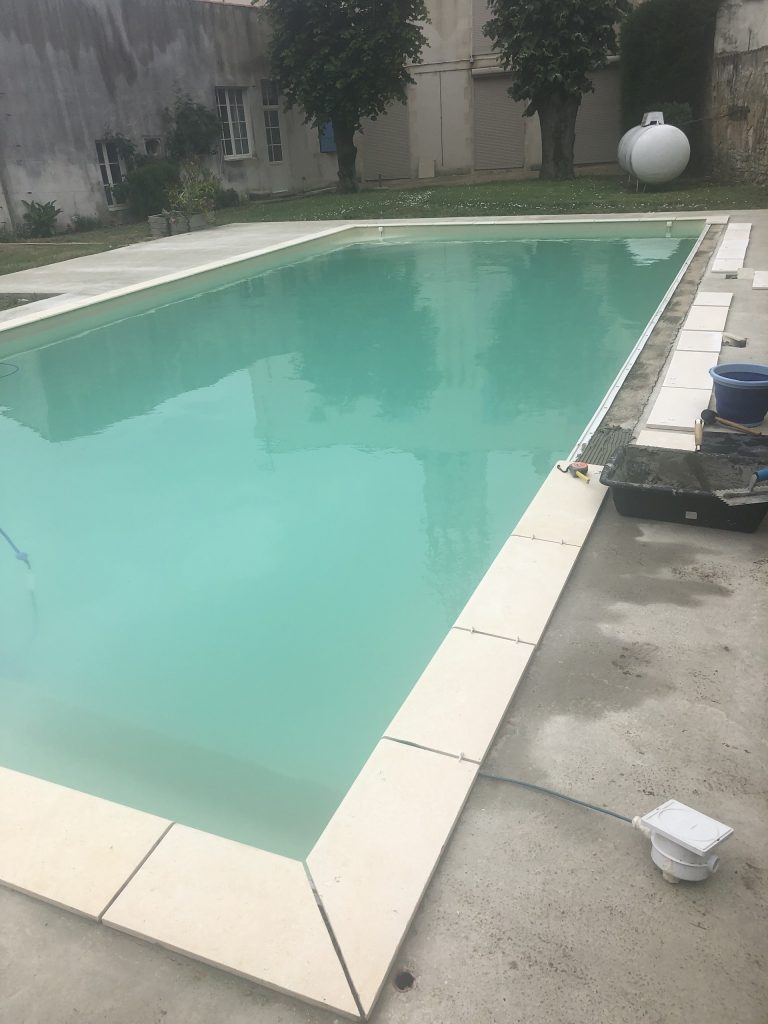 Pose des margelles et dallage en pierre autour d'une piscine à MARANS
