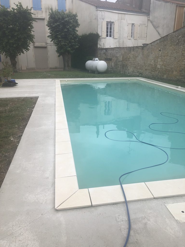 Pose des margelles et dallage en pierre autour d'une piscine à MARANS