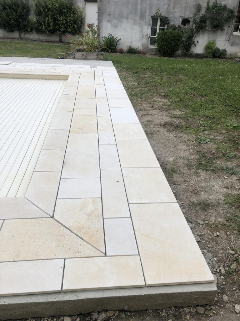 Pose des margelles et dallage en pierre autour d'une piscine à MARANS