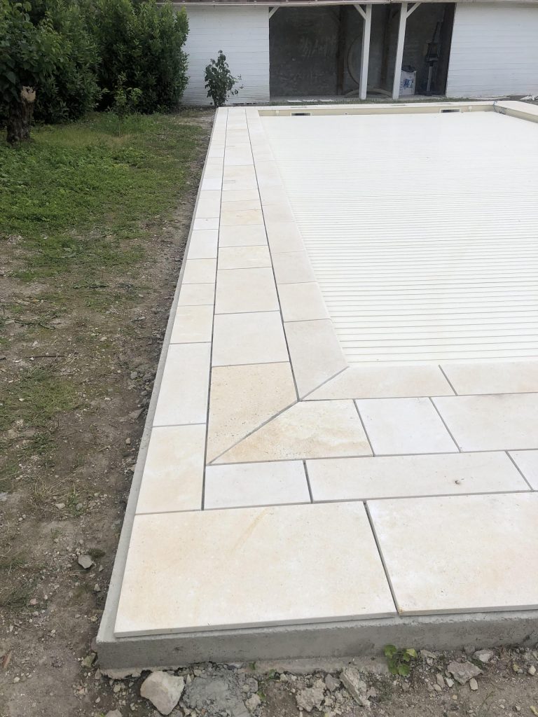 Pose des margelles et dallage en pierre autour d'une piscine à MARANS