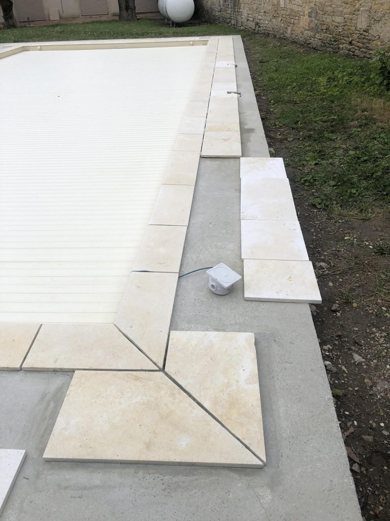 Pose des margelles et dallage en pierre autour d'une piscine à MARANS