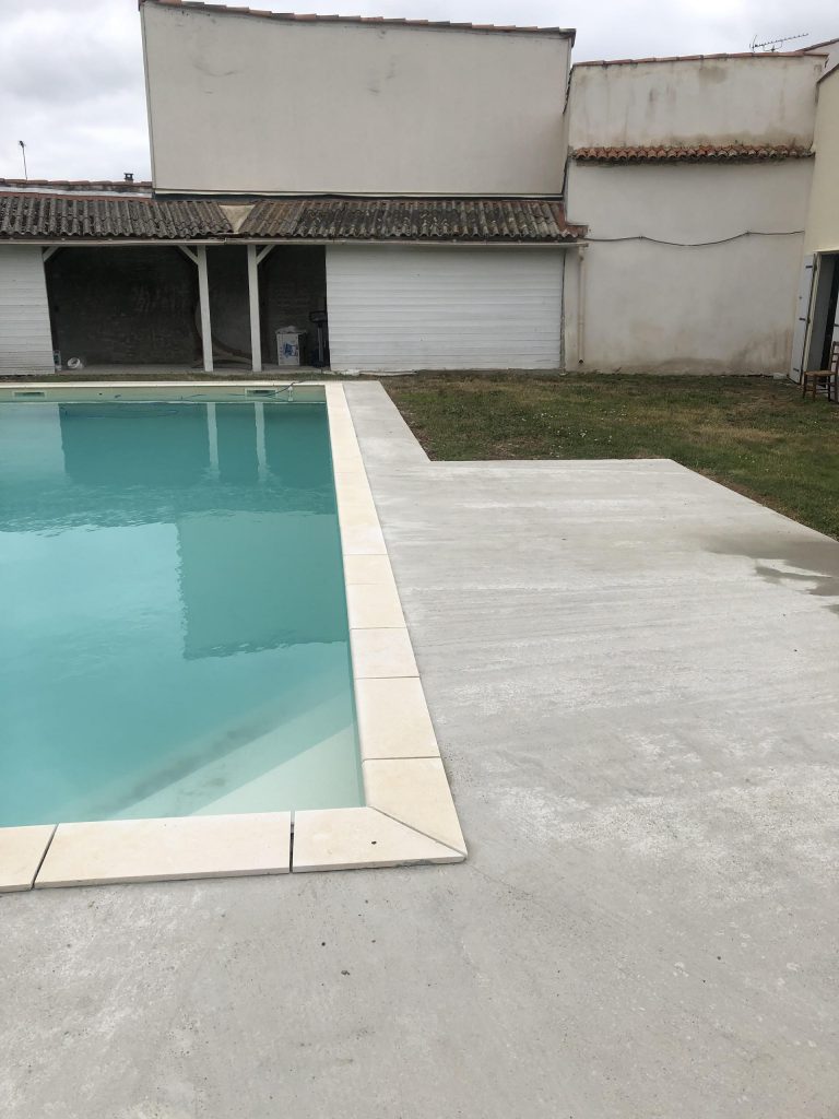 Pose des margelles et dallage en pierre autour d'une piscine à MARANS