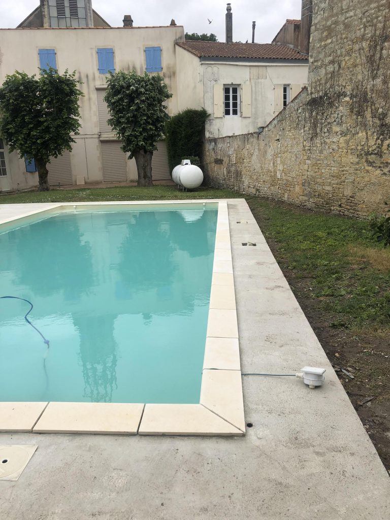 Pose des margelles et dallage en pierre autour d'une piscine à MARANS