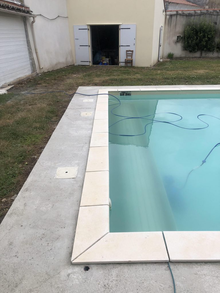 Pose des margelles et dallage en pierre autour d'une piscine à MARANS