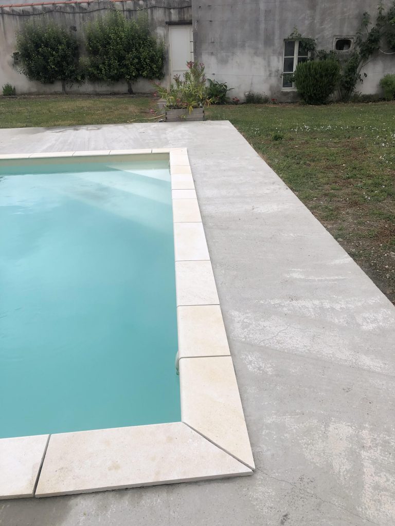 Pose des margelles et dallage en pierre autour d'une piscine à MARANS