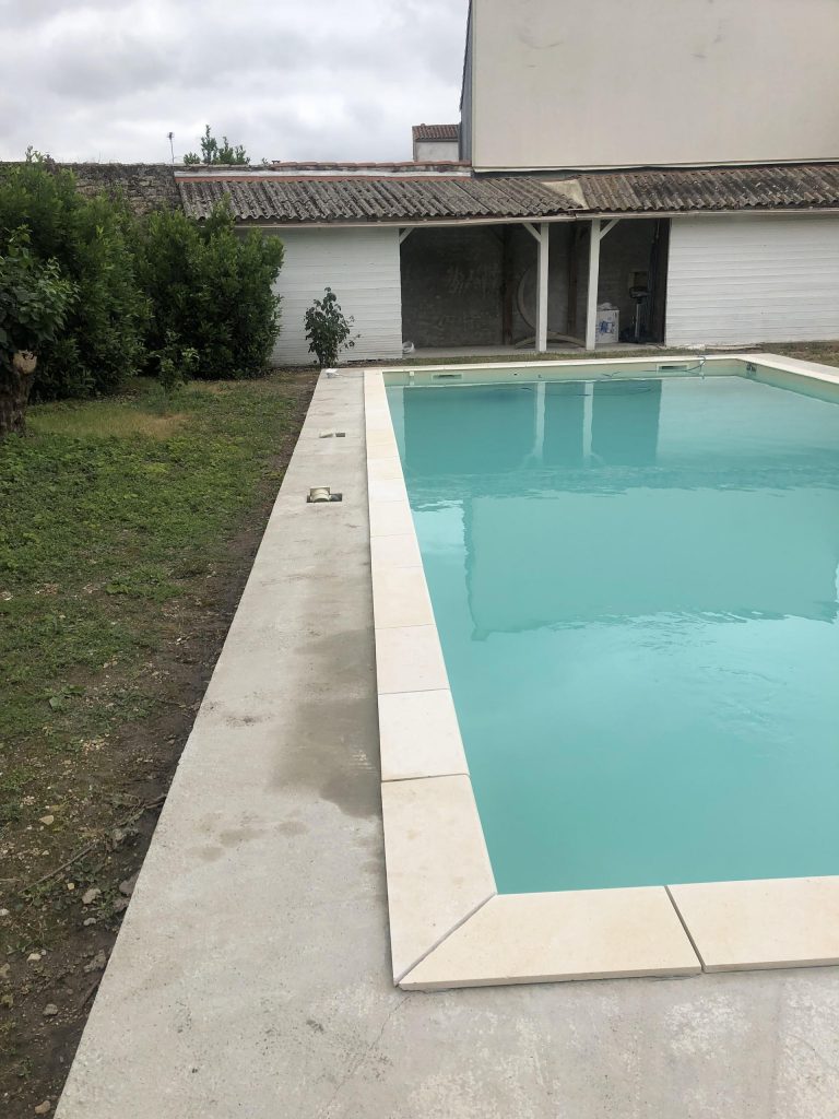 Pose des margelles et dallage en pierre autour d'une piscine à MARANS