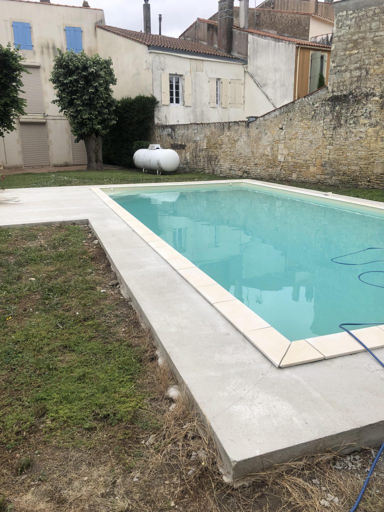 Pose des margelles et dallage en pierre autour d'une piscine à MARANS