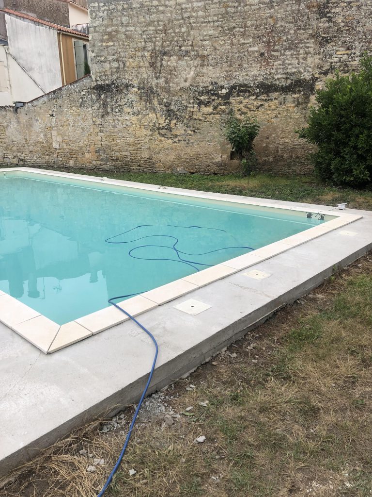 Pose des margelles et dallage en pierre autour d'une piscine à MARANS