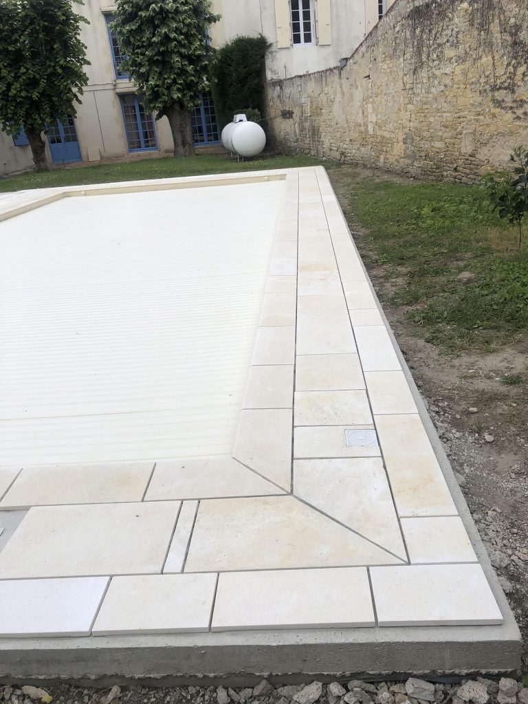 Pose des margelles et dallage en pierre autour d'une piscine à MARANS