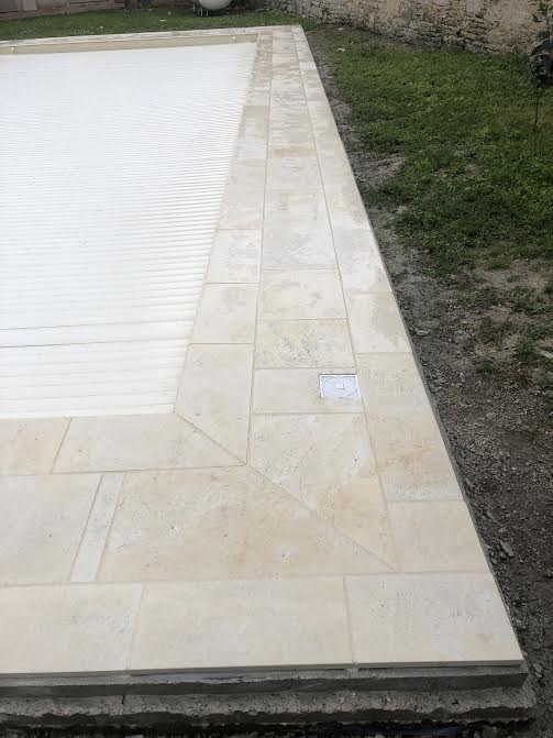 Pose des margelles et dallage en pierre autour d'une piscine à MARANS